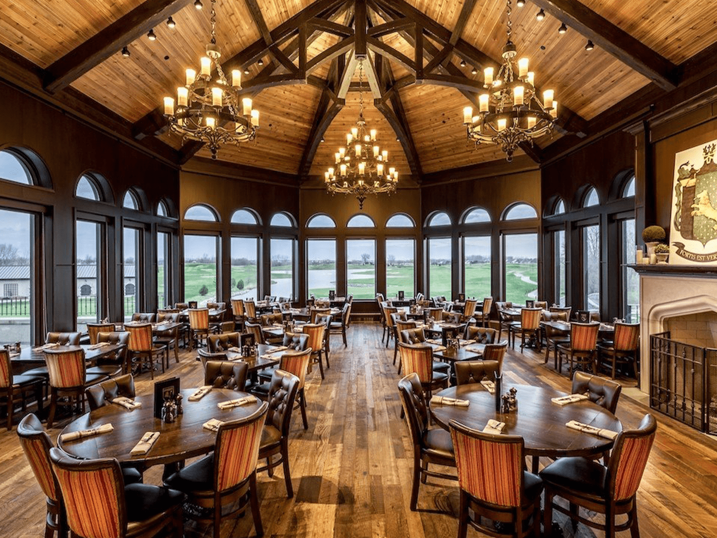 Rustic dining room at McWethy’s Tavern with vaulted wood ceilings, arched windows, and panoramic golf course views.