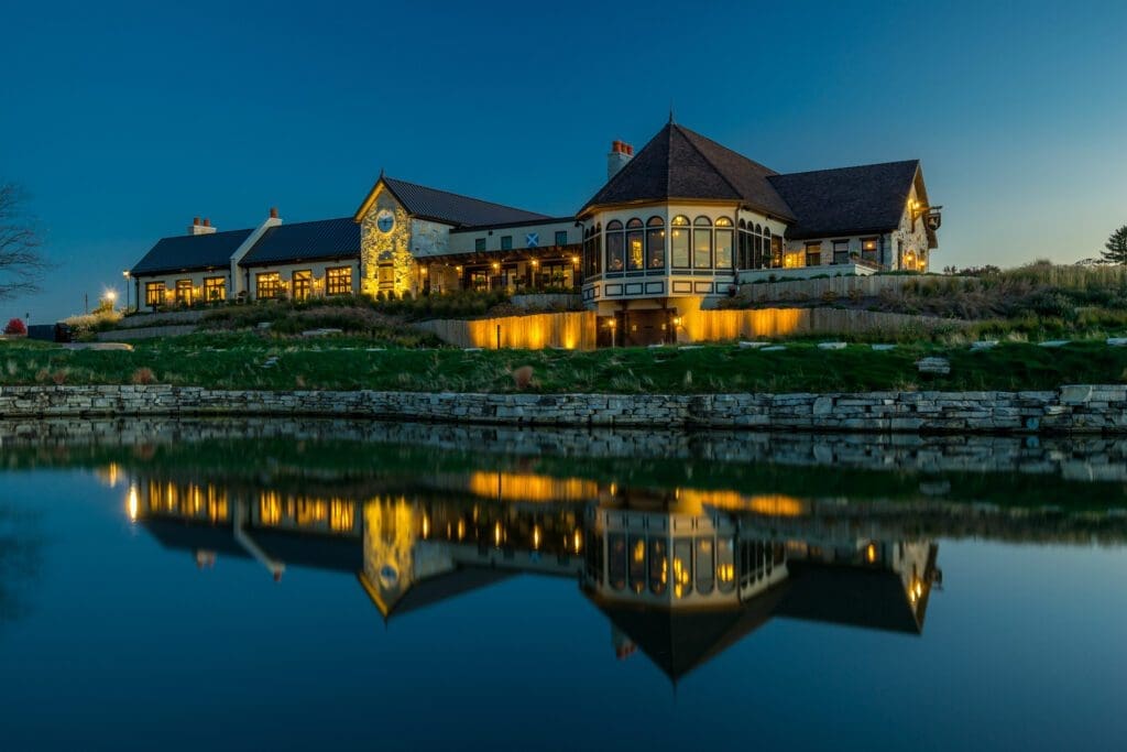 Exterior view of McWethy’s Tavern at Mistwood Golf Club overlooking the lake with warm evening lighting.