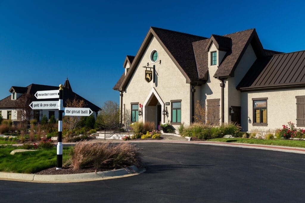 Front entrance of McWethy's Tavern clubhouse with directional signs and landscaping on a sunny day.